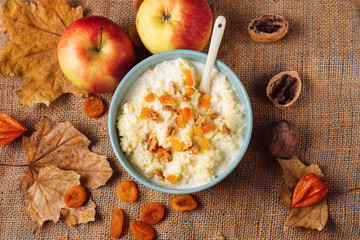 Millet porridge with dried apricots and nuts on the background of autumn leaves - obrazy, fototapety, plakaty