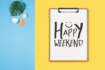 HAPPY WEEKEND text on white sheet on blue and yellow color background