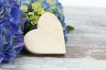 White heart and flowers lying on wood