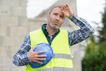 builder man with tired face wipes forehead