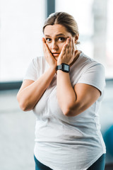 Fototapeta na wymiar surprised overweight woman touching face in gym