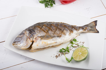 Grilled dorado fish served on a white plate