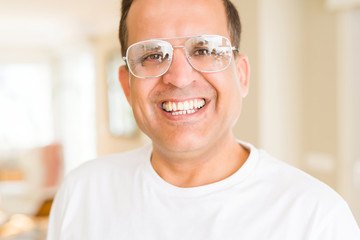 Fototapeta na wymiar Middle age man wearing glasses smiling to the camera at home