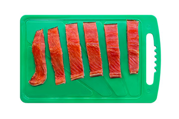 Red chum salmon fish cut into pieces on a green chopping board