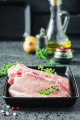 Raw meat, pork steaks on sheet pan with spices, olive oil, herbs, ready for cooking. Selective focus, space for text.