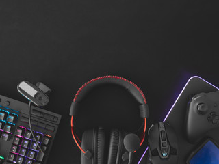 streaming games concept, top view a gaming gear, mouse, Webcams, keyboard, joystick, headset and mouse pad on black table background.
