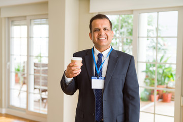 Middle age business man drinking a cup of coffee wearing identification card