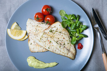 Fried fillet dorado (fish) with tomatoes, lemon and corn salad. Selective focus, close-up.