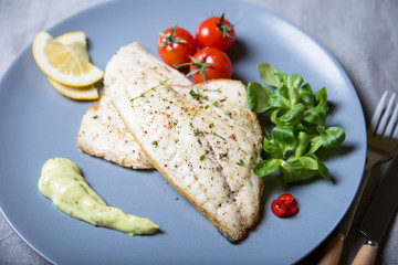 Fried fillet dorado (fish) with tomatoes, lemon and corn salad. Selective focus, close-up.