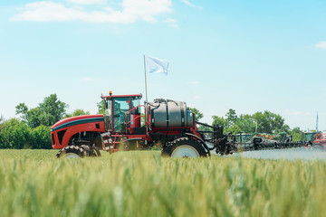 Fototapeta premium Self propelled sprayer watering wheat