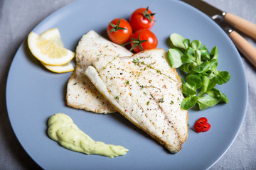 Fried fillet dorado (fish) with tomatoes, lemon and corn salad. Selective focus, close-up.