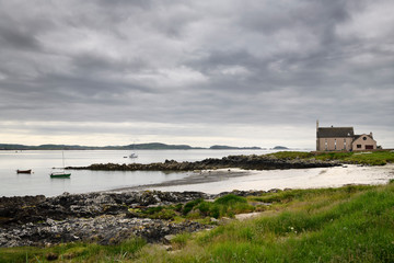 Church converted to a house on the Sound of Iona Martyr's Bay with beach and cloudy skies and sailboats Isle of Iona Scotland UK