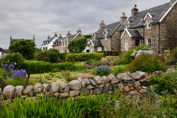 Flower gardens under cloudy sky with stone houses of Baile Mor village on Isle of Iona Scotland UK © Reimar