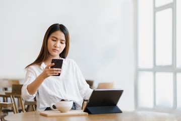 Young beautiful happy asian woman using smartphone and tablet in coffee shop cafe, social network media or online application service concept background