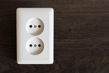 White double electrical outlet on wooden brown background