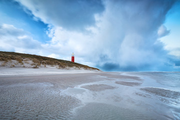 stormy clouds over red lighthouse on North sea coast