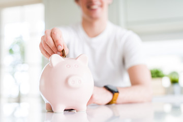 Close up of man putting a coin inside piggy bank as saving or investment