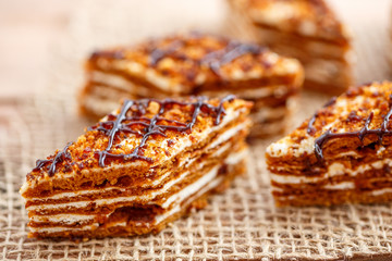 Pieces of cake with layers of cream on the canvas on a wooden table
