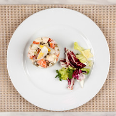 Salad Olivier with egg and cabbage on a white plate.