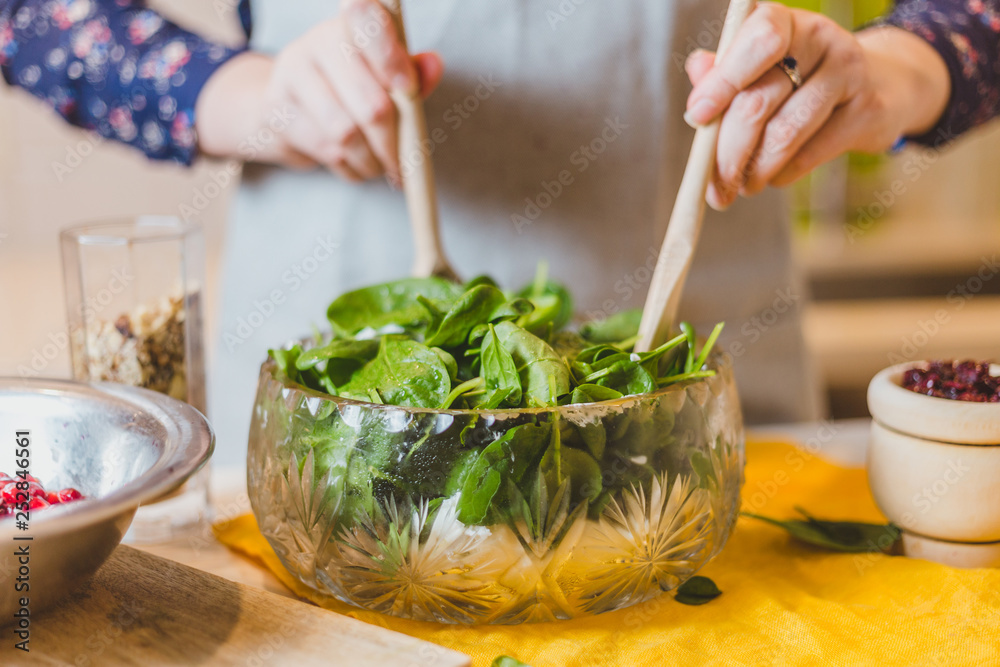 Wall mural housewife mixes salad in a large bowl with two wooden spoons