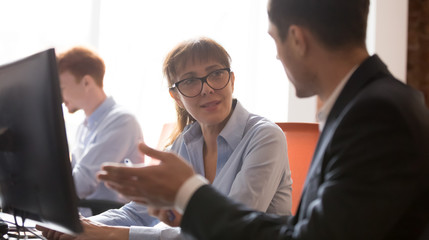 Fototapeta premium Middle-aged businesswoman listening to businessman explaining discussing computer project