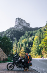 Woman biker and adveture motorcycle on mountain road in Bicaz Canyon, Romania. Travel concept, extreme, vacation in Europe, motorcyclist way, tourism. vertical photo