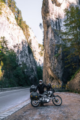 Motorcyclist man on adventure motorbike on mountain road in Bicaz Canyon, Romania. Tourism and vacation concept, moto way, motorcycle extreme tour, best road for motorcycle, vertical photo