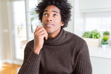 Fototapeta na wymiar African American man wearing winter sweater with hand on chin thinking about question, pensive expression. Smiling with thoughtful face. Doubt concept.