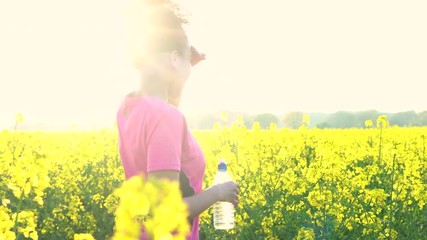 Beautiful healthy mixed race African American girl teenager female young woman resting after running or jogging in field of yellow flowers