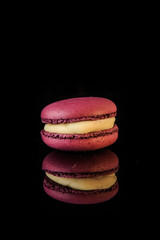 single berry macaroon with yellow filling on black background