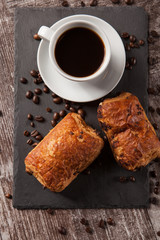 Mug of coffee with delicious pastry and spreaded beans of coffee