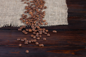 Ripe coffee grains on dark wooden background with linen cloth