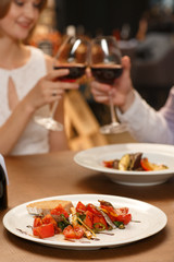 Toast to tasty. Vertical cropped shot of a couple toasting with wine glasses at the restaurant selective focus on food