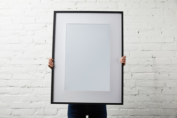 woman covering face while holding blank black frame