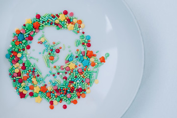 Colorful Holiday Background with multicolored sweet sprinkles on white saucer backdrop. Lovely food web banner, Copy Space for text and design. Easter, birthday greeting card. Top view. Flat lay