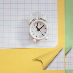 Fototapeta na wymiar Flat lay of school notebooks and alarm clock. Square background with copy space. Starting school, back to school, education