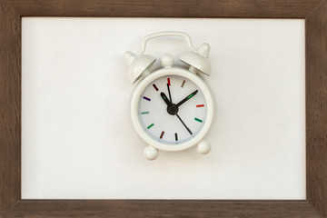 White alarm clock on wooden frame. Concept of time, deadline, countdown. Top view. Background with...