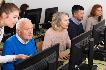 Serious business woman helping to male partner, pointing at computer monitor