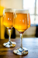 Two glasses of beer are on the bar table.