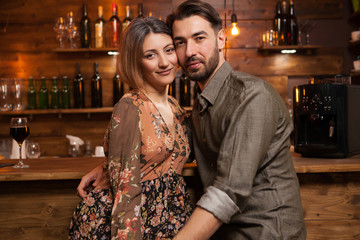 Attractive couple celebrating their aniversary and looking at the camera in vintage pub