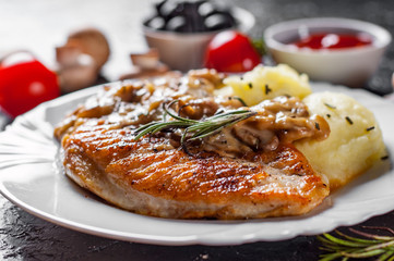 roasted Chicken Breast with Mushroom Sauce and mashed potato in white plate on dark background