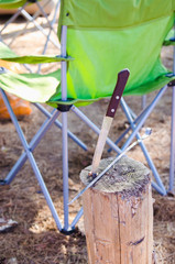 Fototapeta na wymiar Folding chair and knife on the stump camping concept