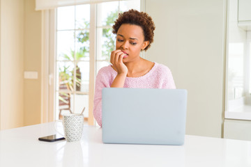 Young african american woman working using computer laptop looking stressed and nervous with hands on mouth biting nails. Anxiety problem.