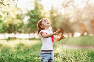 A portrait of a cute little girl smiling in the garden on a nice summer day and looking at a...