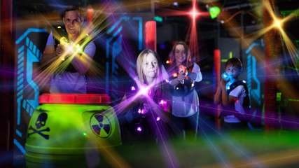 Fototapeta na wymiar Parents and children playing laser tag in beams