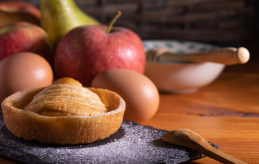 homemade apple pie on a wooden table with fruit in the background