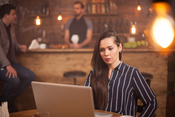 Young beautiful woman working on her laptop in vintage coffee shop.