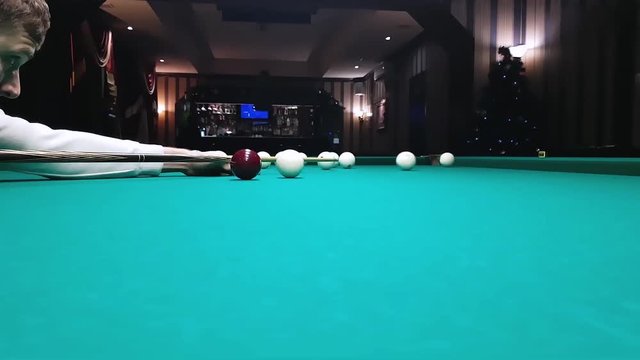 young handsome man puts a billiard ball in the pocket