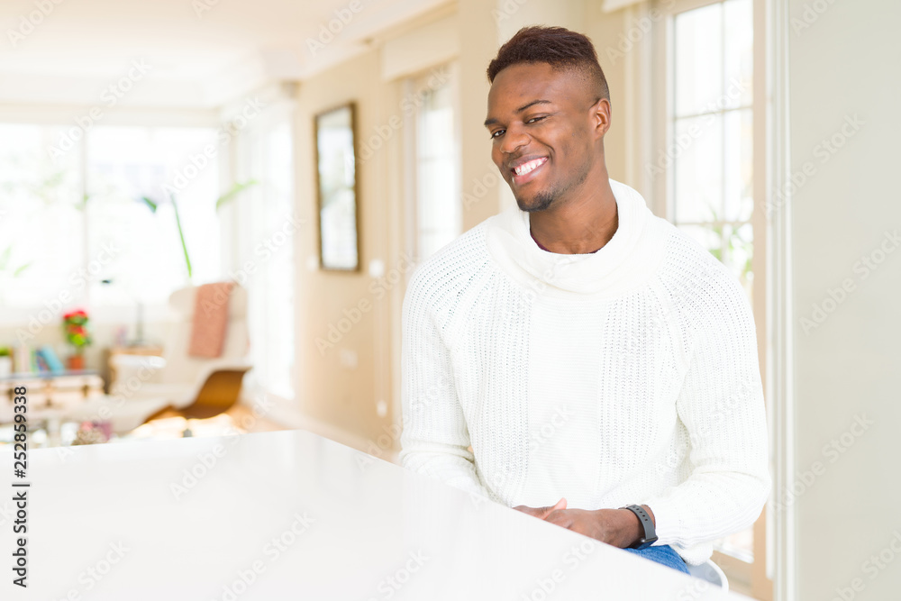 Wall mural handsome african american man on white table looking away to side with smile on face, natural expres