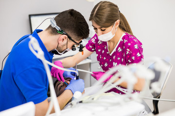 Male dentist with assistant examining girls teeth in the dentists chair. Dental clinic